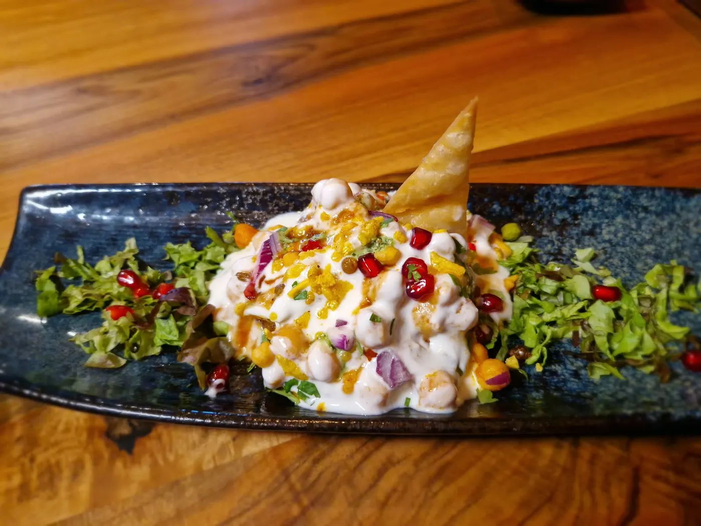 Street-Food-Teller mit Kichererbsen, Joghurt und Granatapfel auf schwarzer Platte