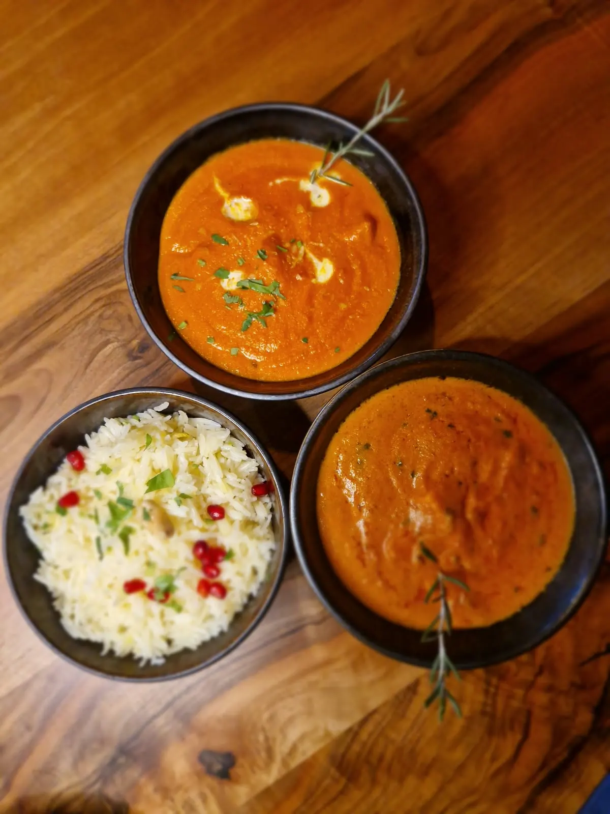 Zwei Curries und Basmati-Reis mit Granatapfel auf dem Holztisch im Kahani