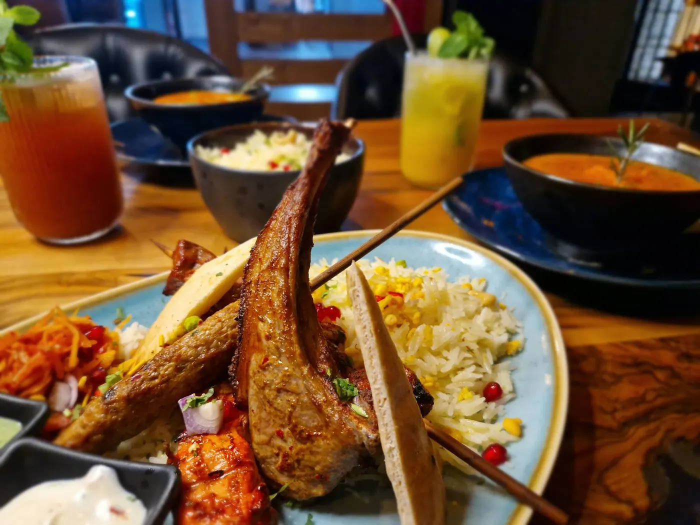 Grillteller mit Lammkotelett, Seekh Kebab und Tikka auf hellblauem Teller