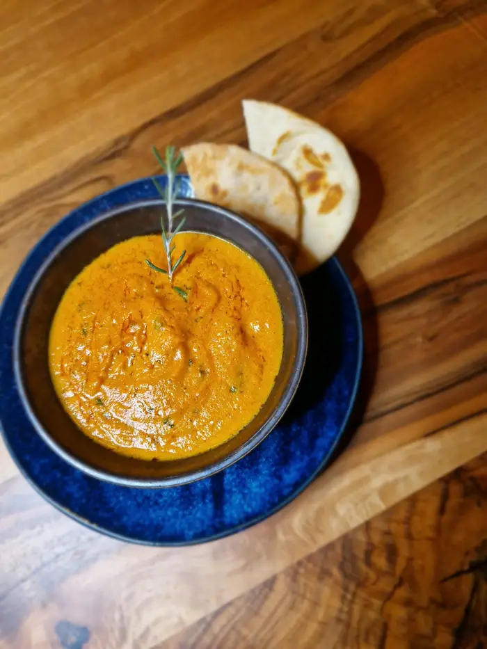 Curry in blauer Schale mit frischem Naan