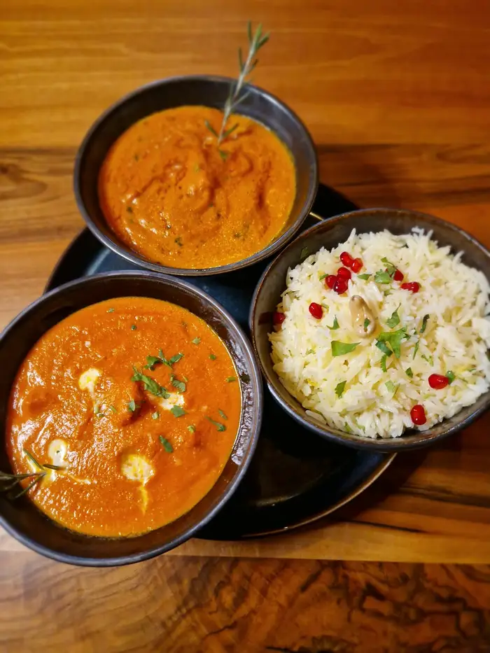 Zwei Curries und Basmati-Reis in dunklen Schalen